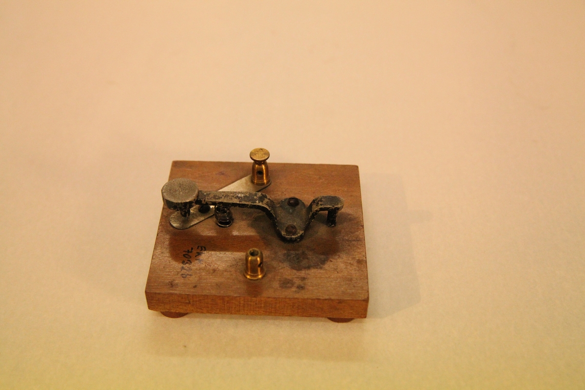 Morseapparat med sender og mottaker. Mottakeren har rull med blåpapir som setter merker ved hvert tegn. Må sveives manuelt.