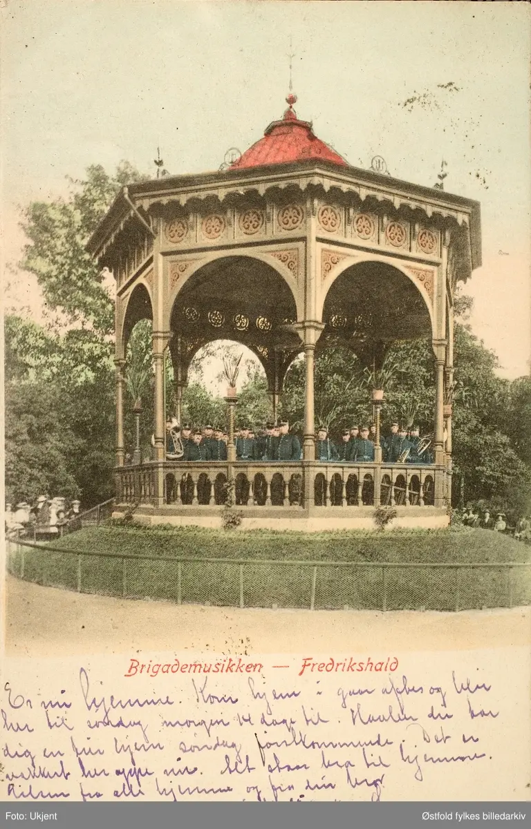 Postkort, kolorert lystrykk av paviljong i Halden der Brigademusikken spiller, 1903.