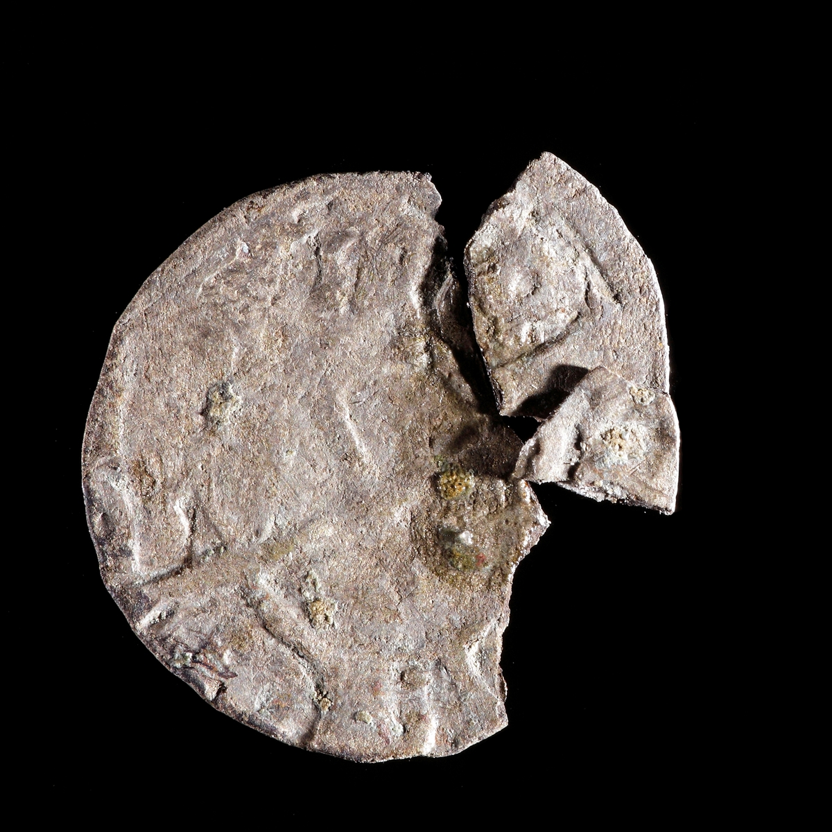 1 hvid silvermynt, Kristian I, Danmark (Galster 23d samt Hgb s. 186:35). Åtsida med krönt R och frånsida med kors. Lagad, men i sönderfall.