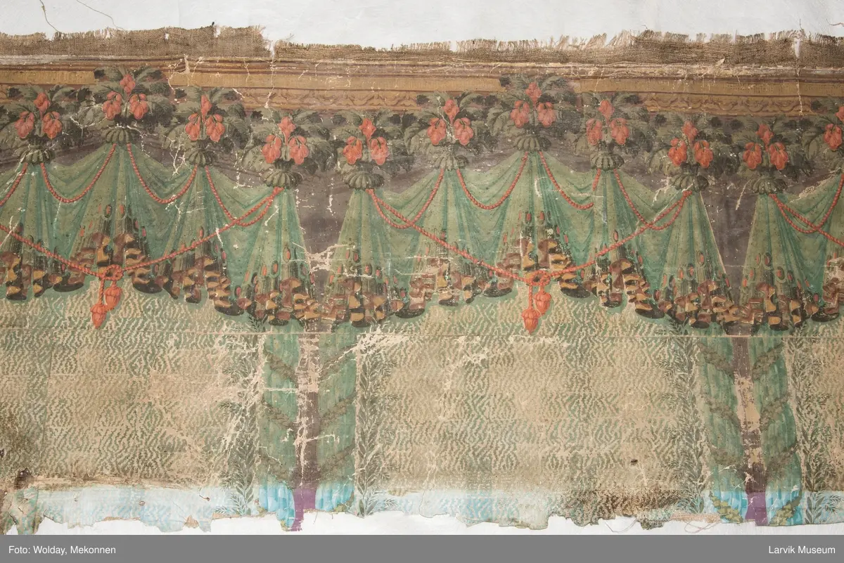 |Tapeten er påmalt tapetborder og brystning. Fra Hovland gård i Larvik.
Den øverste, brede borden: Gerlander/draperi med blomsterranker.
Den nederste, smalere borden: Tekstilbord med blomster. Øver døren til høyre: Stillebenmotiv med blomster og frukt.