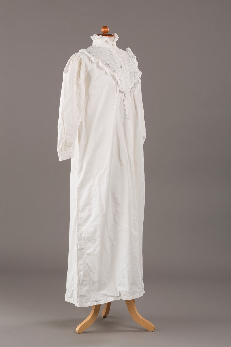 Form: Lange ermer, fotsid.

Blondekant og rysjer i halsåpning.
To knapper i metall kledd i tekstil. Mangler en knapp.