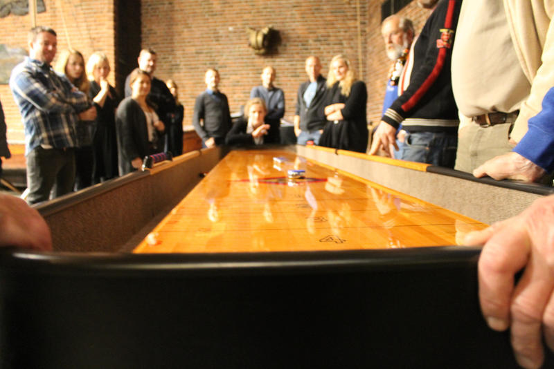 Shuffleboard i vestibylen på Norsk Maritimt Museum, nærbilde av den ene enden, mange folk rundt.