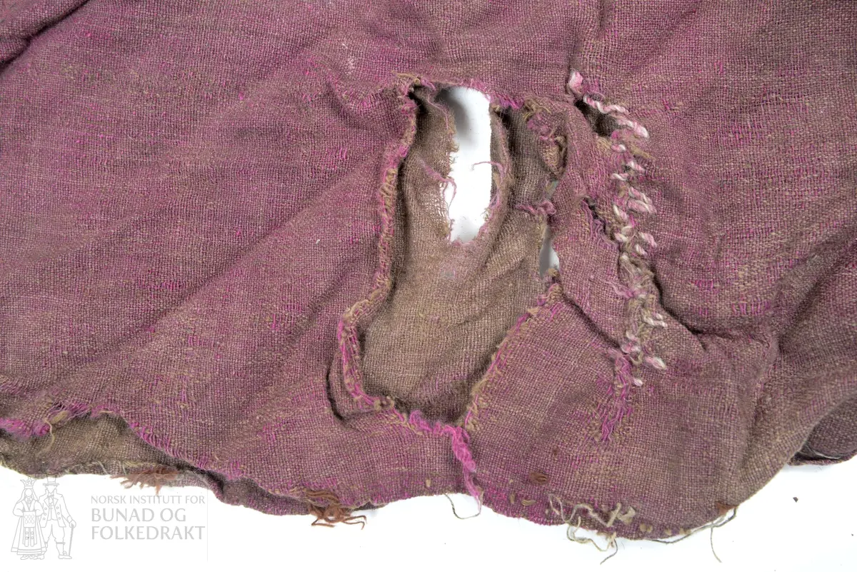 Del av ein stakk, full høgde utan linning. To høgder av brun og lilla verken, lerretsbinding med ull i innslag og renning, sauma saman for hand. Stoppa med eit stort stykke midt på høgda og to gonger i nedkant, truleg med sama stoff som stakken, bortsett frå eine bota i nedkant som er eit stripete stoff i raud, svart og brunt. Framstår som utslitt i fargen med fleire hol etter mus, har vore nytta som stappefille.