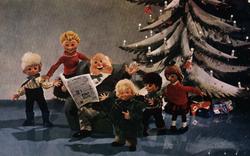 Julekort. Ubrukt. Interiør. Dokkefamilie foran juletre. Far 
