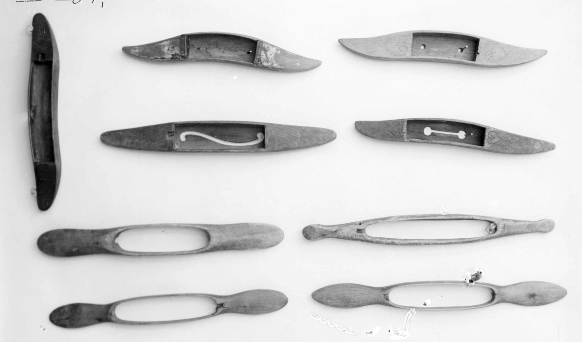 Vevskyttel av tre med lange håndtak på hver side. I midten er det skåret ut et hull, med plass til trådspolen.