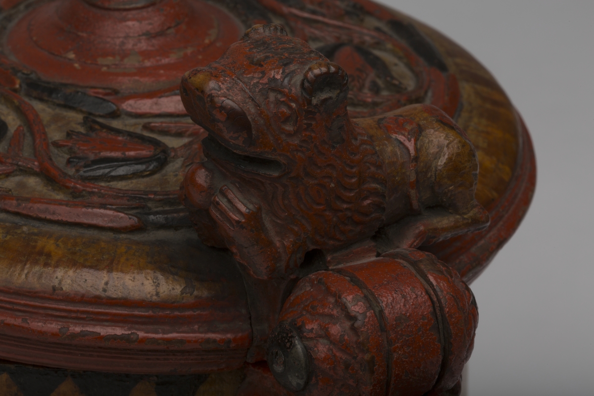 Dekorert med fortløpende billedfrise med dyr og trær på nederste del av korpus. Kannen har løveføtter og løvegjekk og bakkantine som håndtak. 