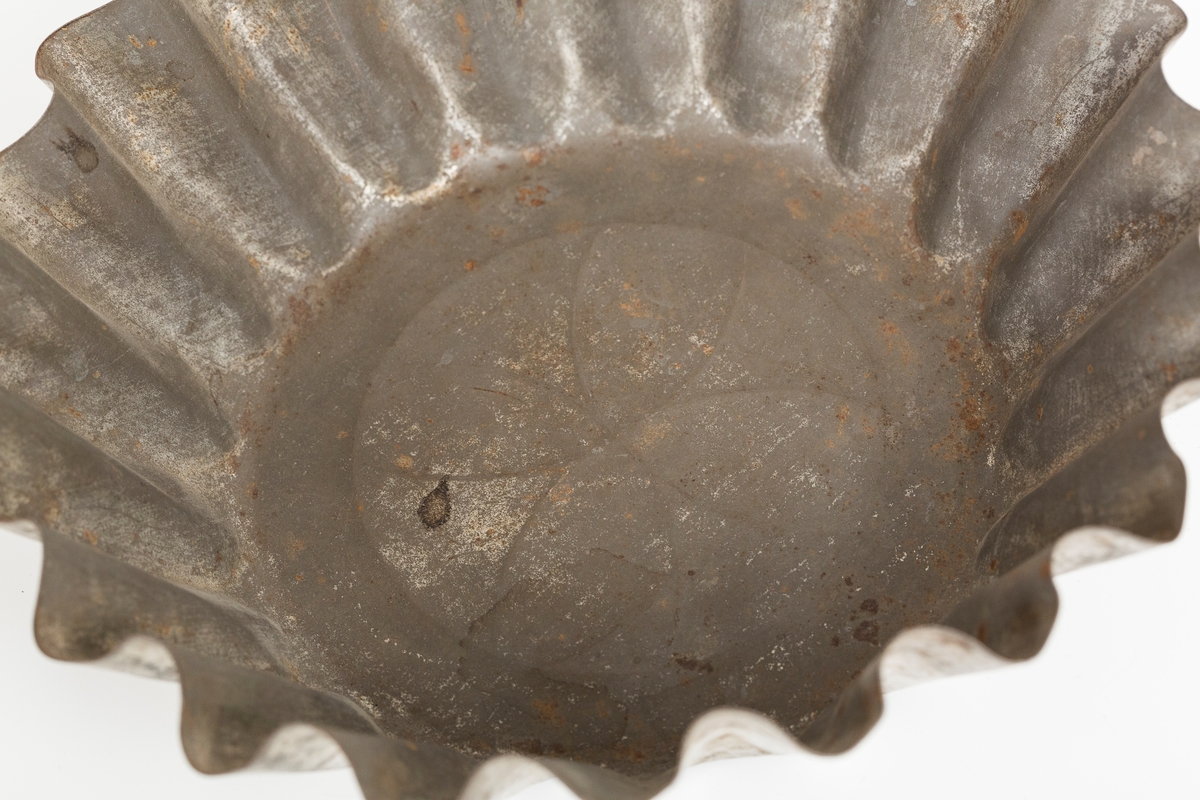 Kakeform for terte, også kalt terteform. Blomstdekor på bunnen av formen. Noe rust på formen.