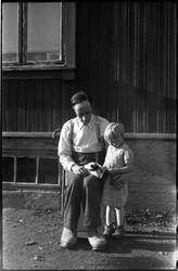 Sigurd Røisli og dattera Sigrun med kattunge i husveggen hje