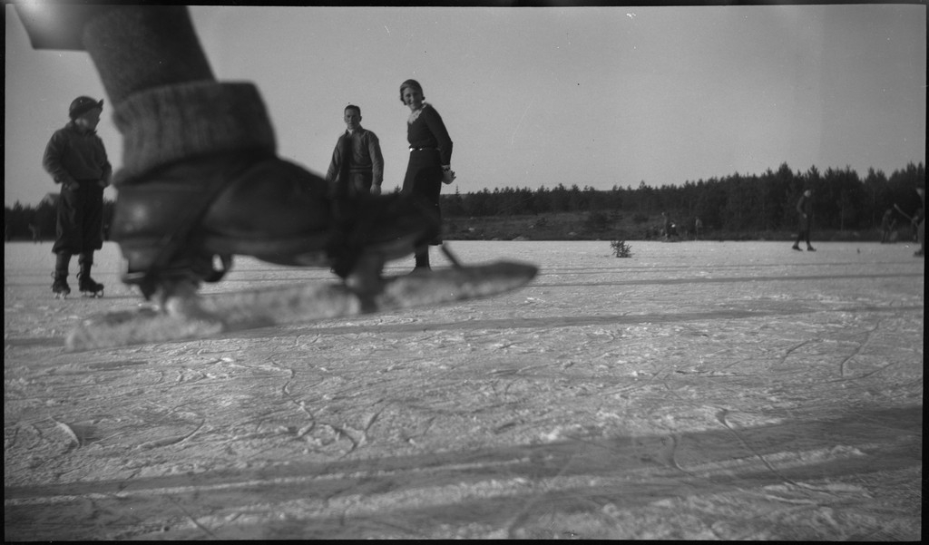 Lindtner og Finn Johannessen med en familie på skøytetur på Gisketjørn i Sandnes. Barna spiller bandy eller ishockey med hjemmelagde køller.