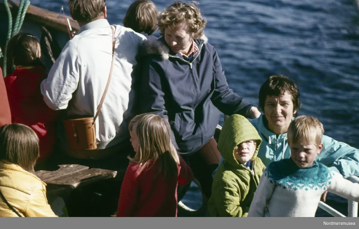 Foto av en en gruppe mennesker på tur til fiskeværet Grip i Kristiansund kommune. Fotograf er Kjell Haug og er den som står bak samlingen med fargefoto/dias fra Kristiansund og Grip. Bildene dateres til omkring 1950-1970. Fra Nordmøre museums fotosamlinger.