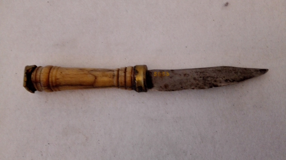 1kniv.

Bordkniv med dreiet, 7,6 cm langt benskaft med messingholker i begge ender.
Gave fra gaardbruker Nils Stjernegjerdet, Feios.