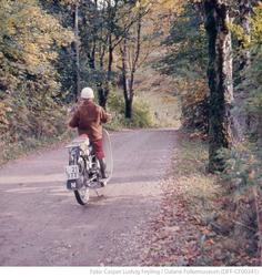 Liten gutt sitter på moped