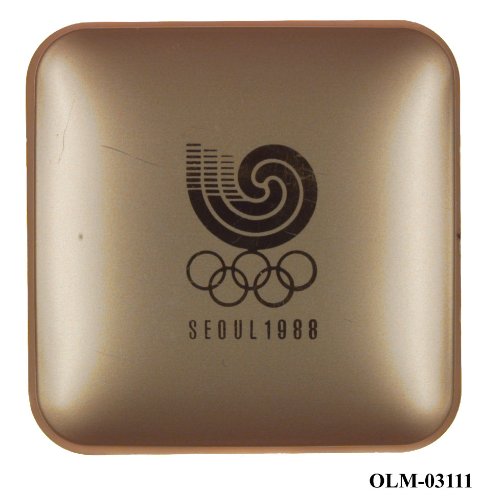 Mynt som viser to barn p den ene siden og og seks lotusblomster under jing yng symbol på den andre siden. Mynten ligger i en sølvfarget eske merket Seoul 1988.