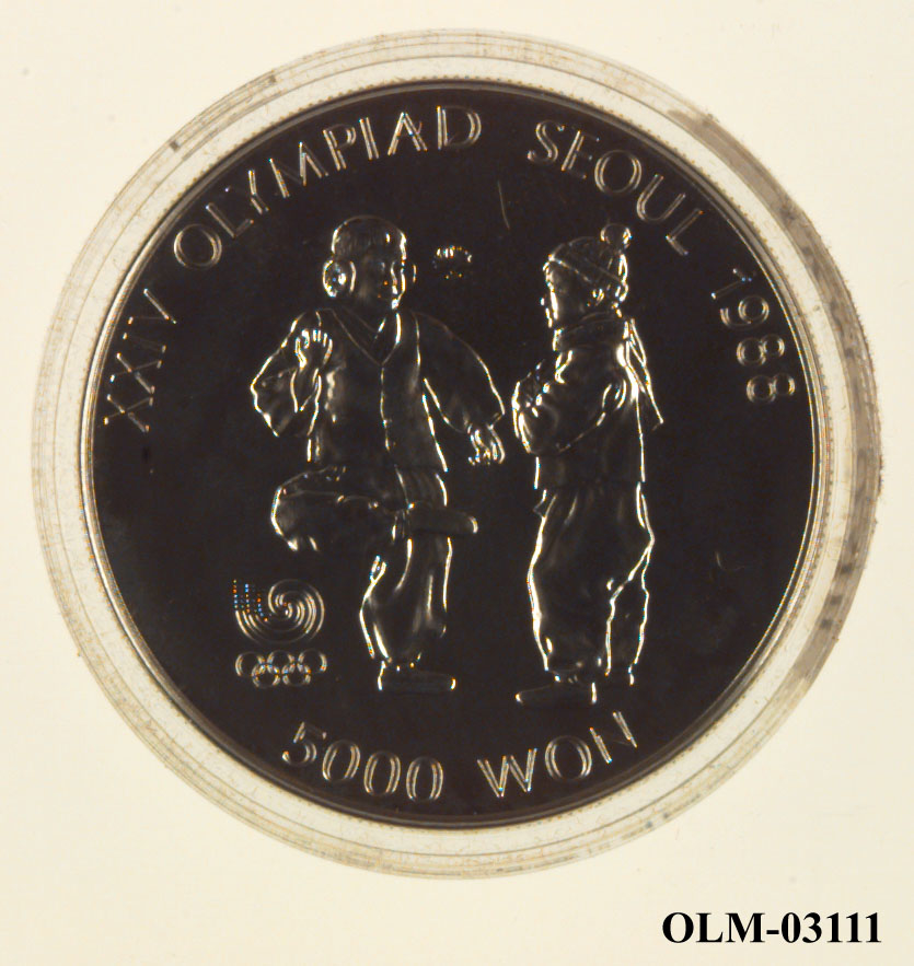 Mynt som viser to barn p den ene siden og og seks lotusblomster under jing yng symbol på den andre siden. Mynten ligger i en sølvfarget eske merket Seoul 1988.