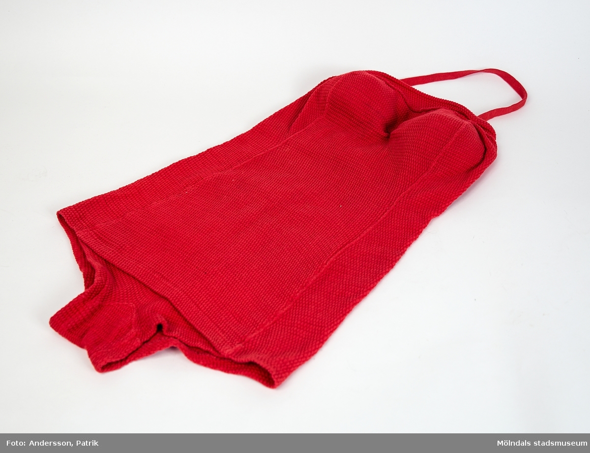 Röd baddräkt som är tillverkad av AB Klaraviks Tricotfabrik troligtvis på 1960 eller 70-talet.

Baddräkekten är tillverkad av specialbehandlat yllegarn för att bibehålla passformen.

I baddräkten finns fastsydda etiketter med tryckt: storlek och varumärke.