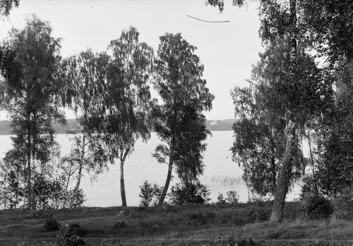 Utsikt över en sjö och i bakgrunden skymtar man Näsby kyrka utanför Vetlanda i Jönköpings län.