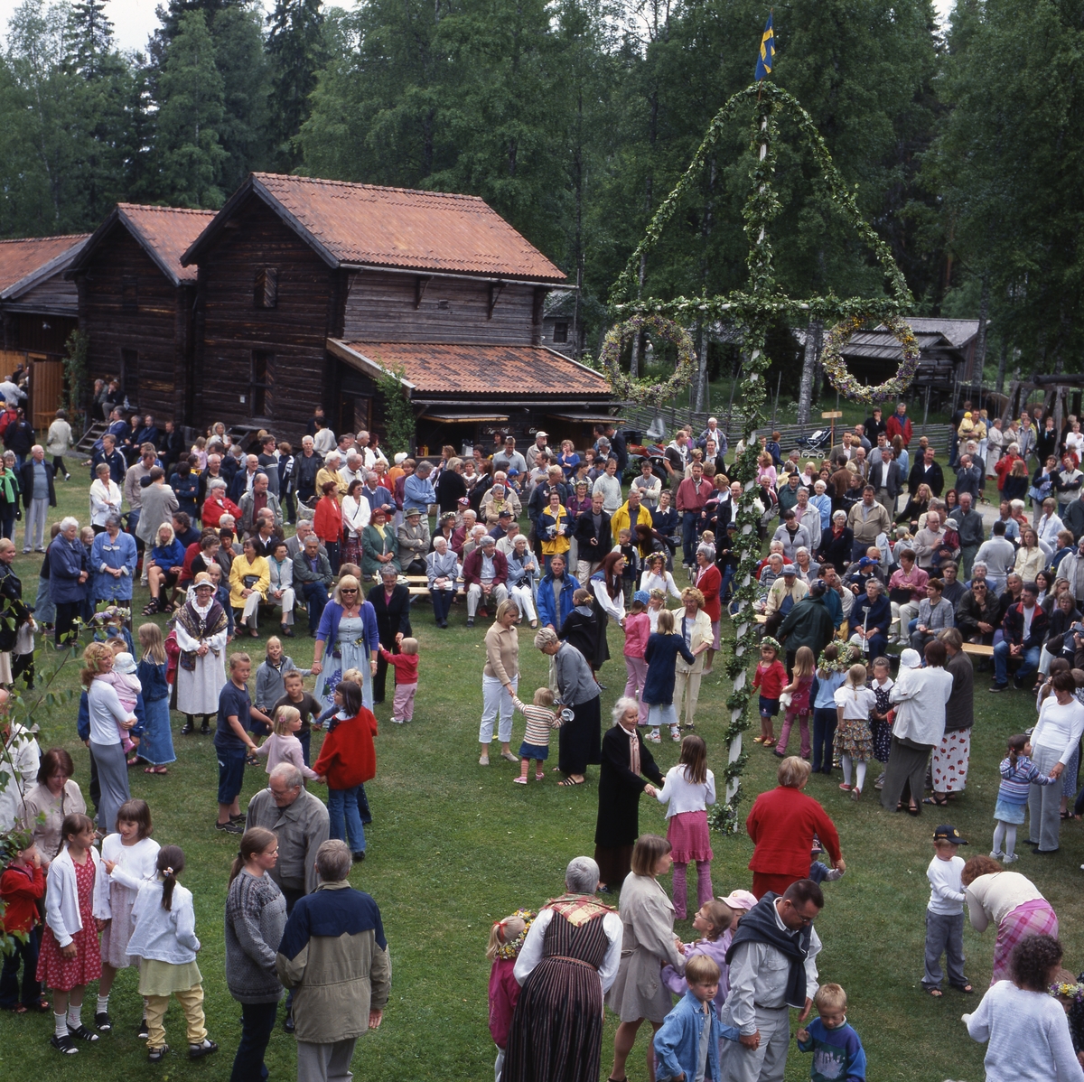 Midsommarfest vid hembygdsbyn Västerby i Rengsjö, midsommarafton 22 juni 2001. Många besökare är samlade vid midsommarstången för lekar och dans.