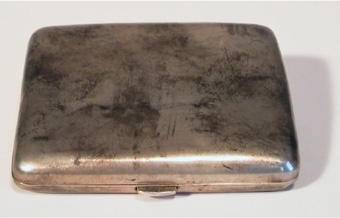 Delbart rektangulärt cigarettetui av silver, invändigt förgyllt. Försett med gångjärn och trycklås. Invändigt två resårband som är fästade i bottens sidor.