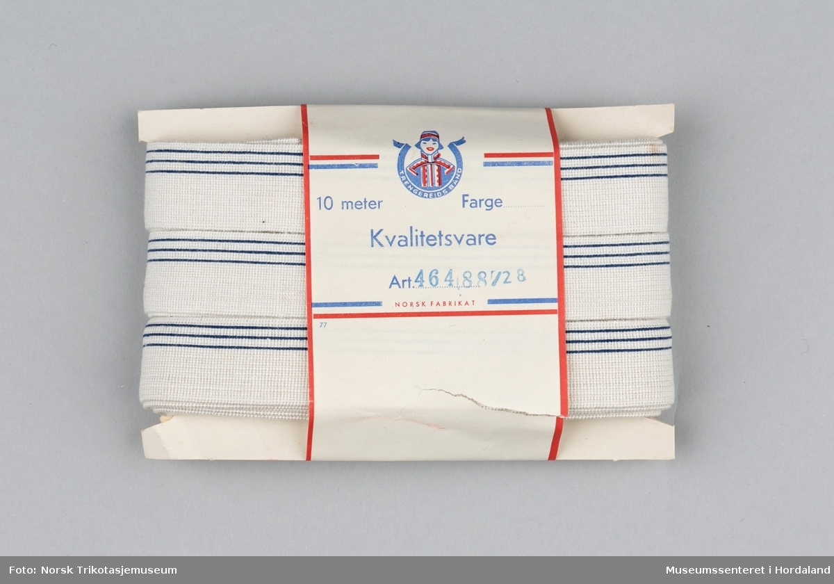 Kvit strikk/elastikk med mørkeblå striper, med papp/papiremballasje. Produsert ved Trengereid Fabrikker.
