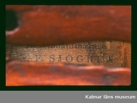 KLM 39521 Fiol, av trä. Fiol med tre stämskruvar. Stränghållare, stall och strängar saknas. Försedd med invändig tillverkaretikett, text: Förfärdigad af Instrumentmakare N. F. Sjögren i Calmar 1829.