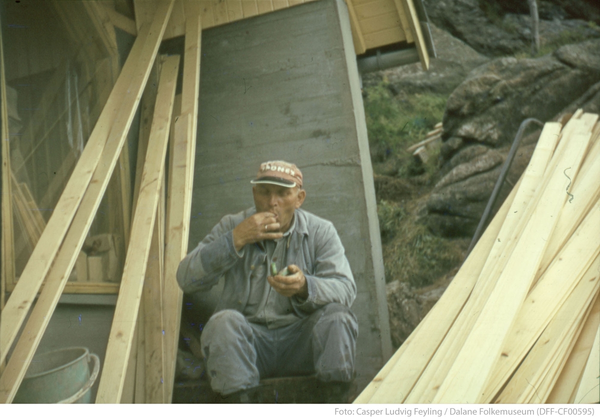 En mann tar en pause i en trapp mellom byggematerialer
