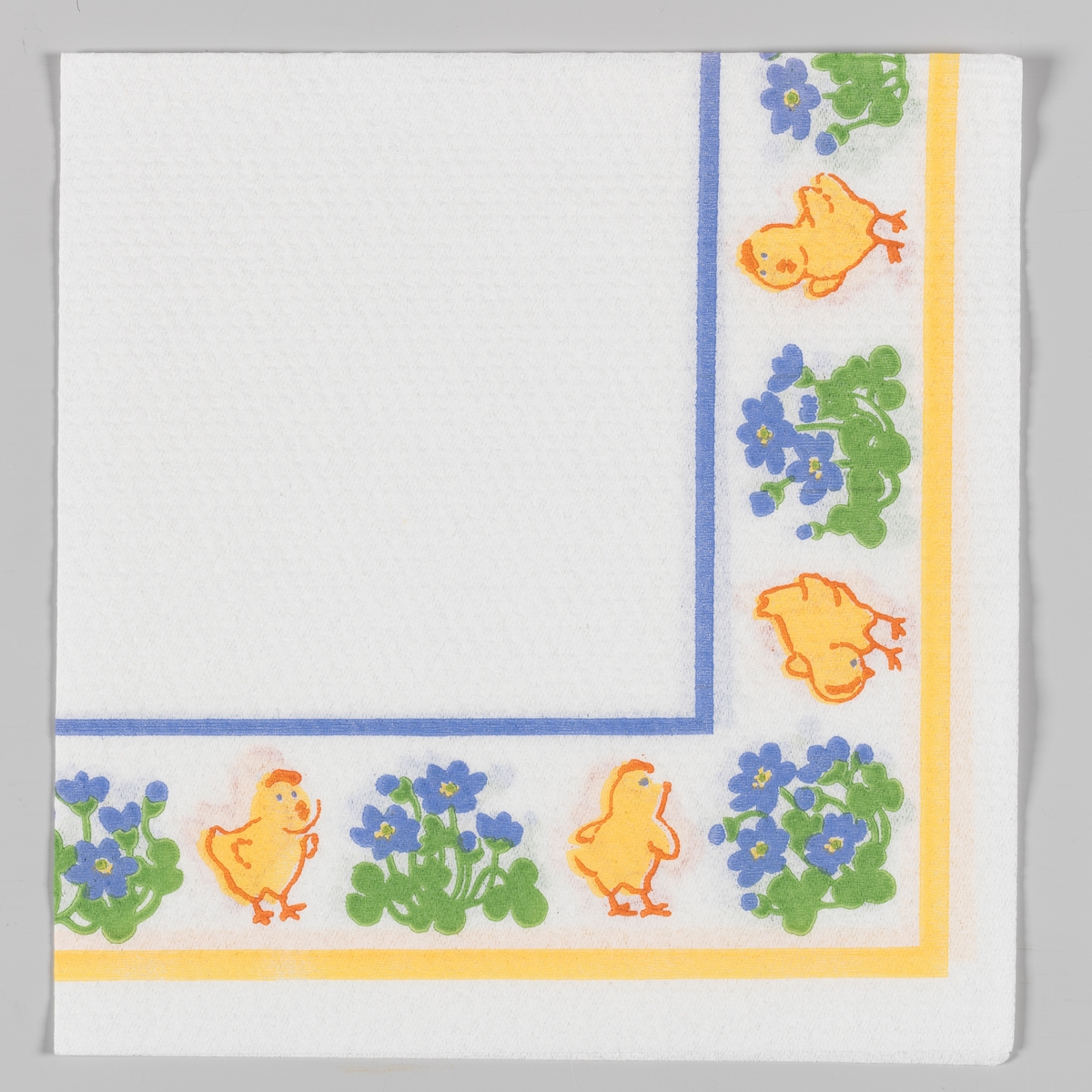 Kyllinger og blå blomster langs kanten av servietten. Blå og gule kantstriper.