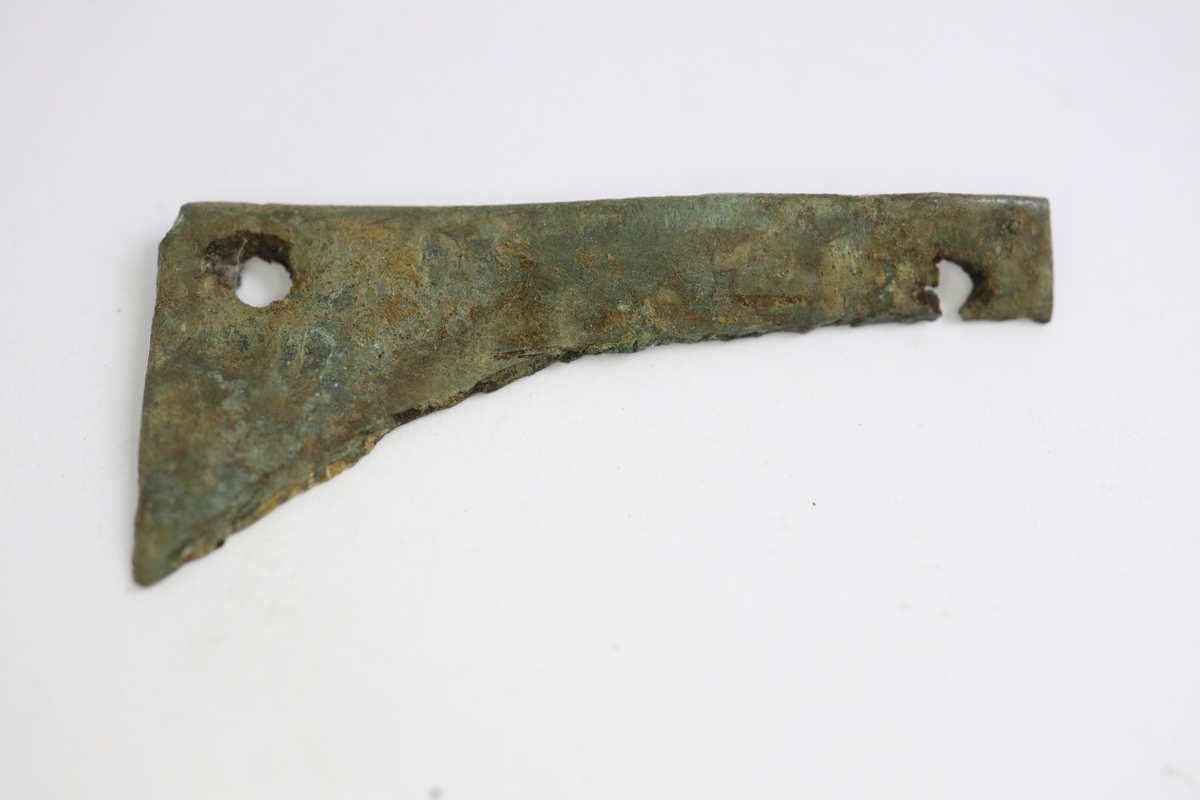 Fragment av ett beslag (?) bestående av ett avklippt stycke rätvinkligt bronsbleck med två nithål.