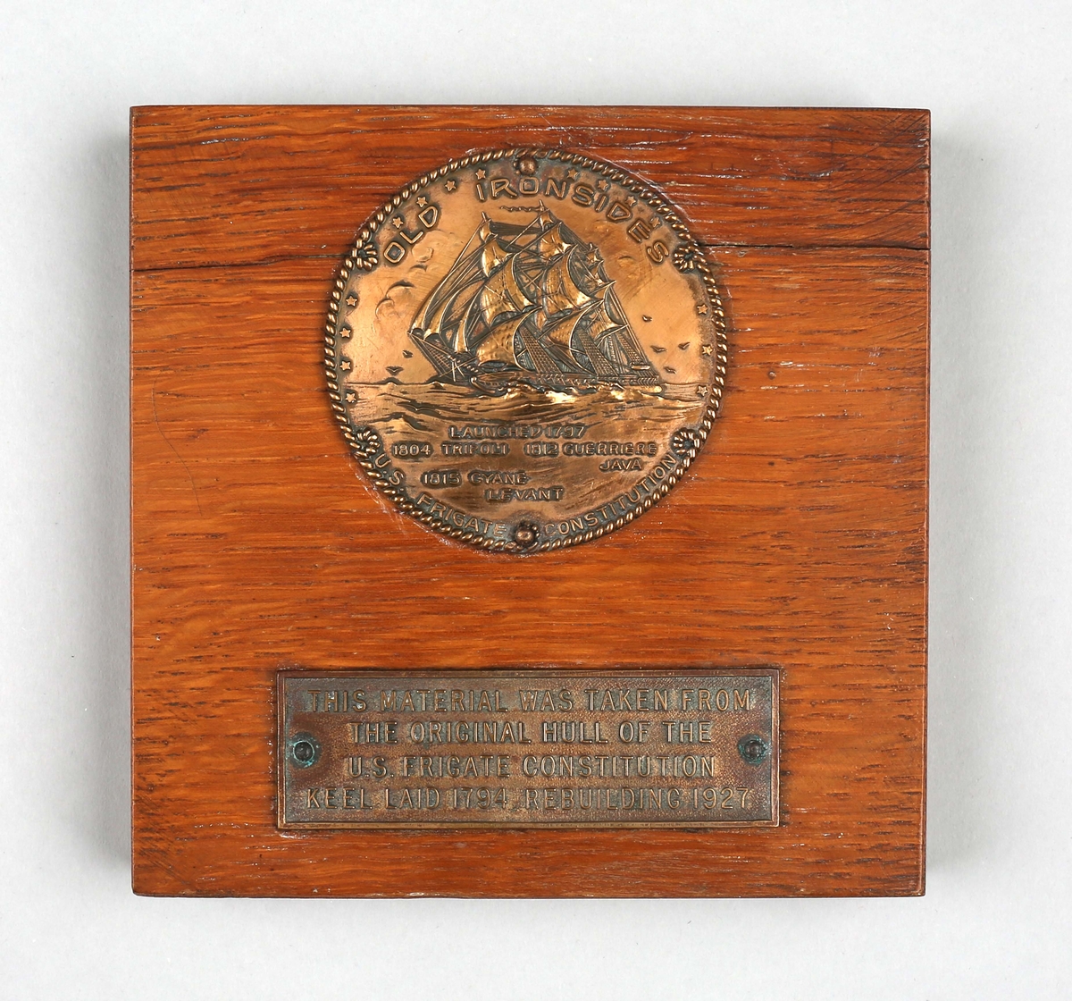 Plakett i tre med minnemedalje med motiv av fregatten CONSTITUTIONEN som var sjøsatt i 1794/1797 og ombygd i 1927.