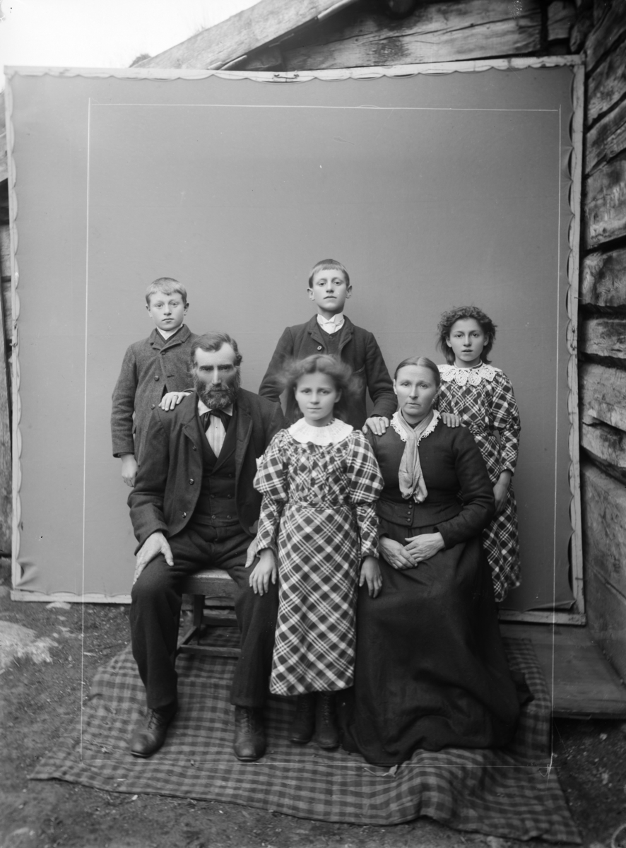 Atelierfoto (provisorisk ved lafta bygning) med familiebilde fra garden Gjershaug, Verma i Romsdal. Bildet viser foreldre, to jenter og to gutter.
