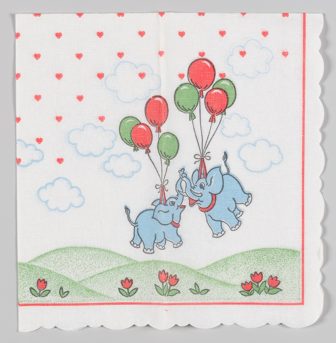 To lyseblå elefanter flyger avgårde båret av ballonger. Under elefantene er det et bølget grønt landskap med blomster. På himmelen er det lyseblå skyer og masse hjerter. En rød stripet kant.