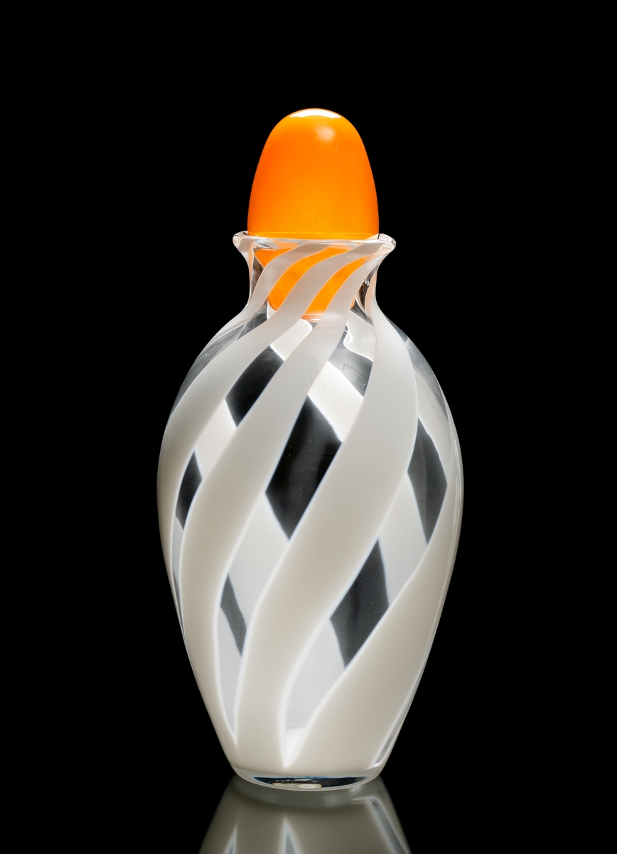 Urna "VIVA" i ofärgat glas med stående, vridna, vita fält. Propp i orange opakt glas.
