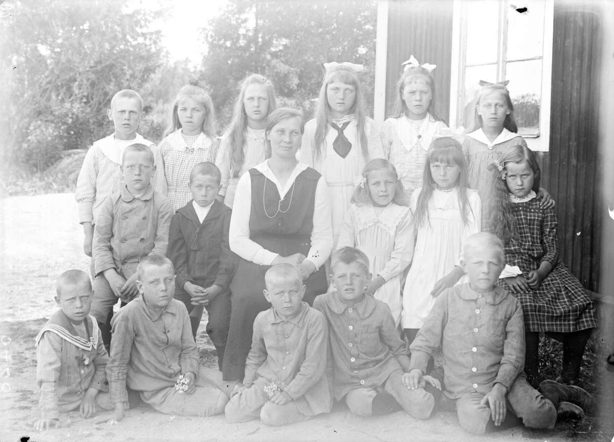 "Skolbarnen vid Storbo skola i Simtuna med lärarinnan Lisa Ekstrand utanför skolan, Uppland 1921