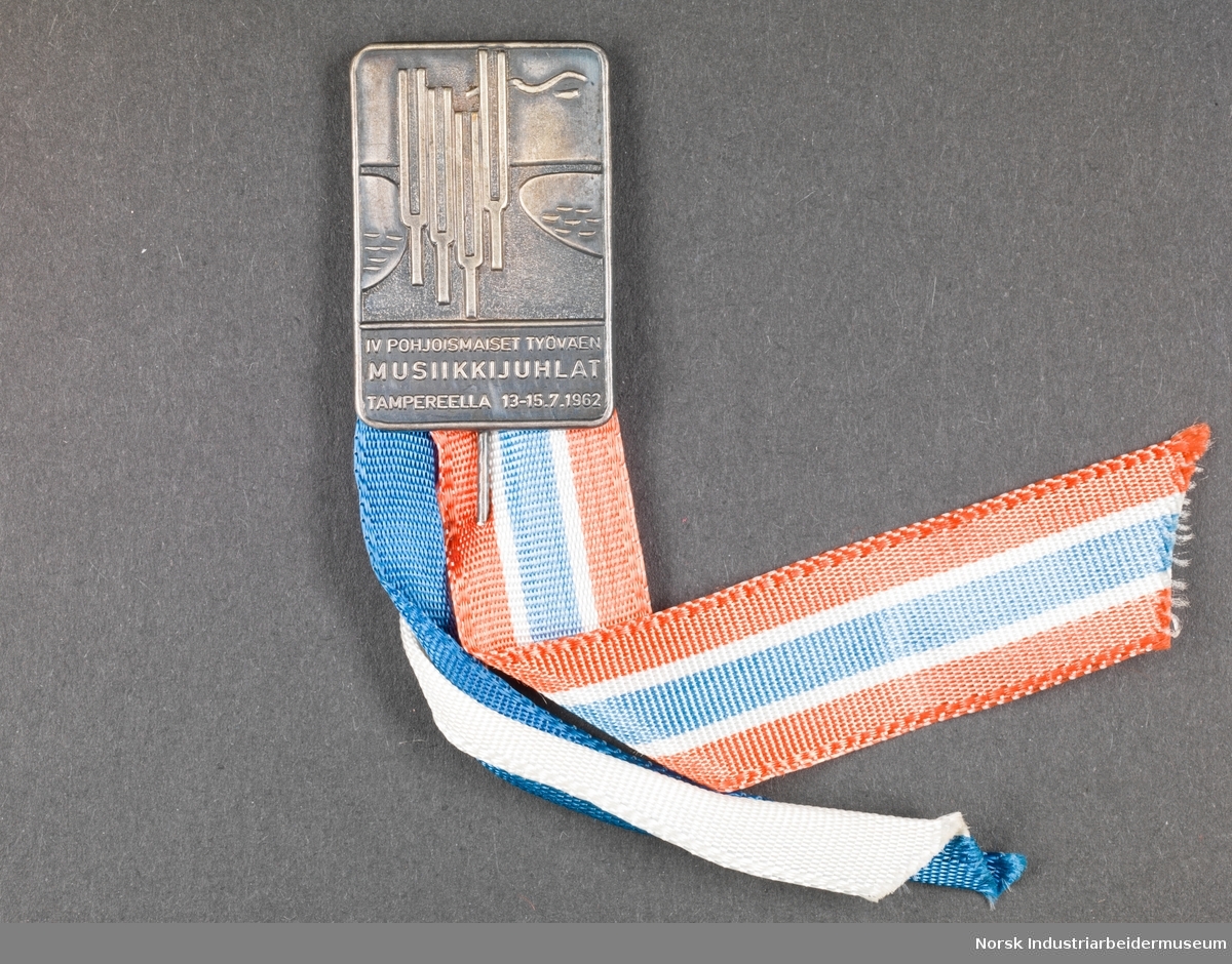 Rektangulær medalje. Motiv på forside med tekst under. Bånd av henholdsvis Norges nasjonalfarger og Finlands nasjonalfarger.