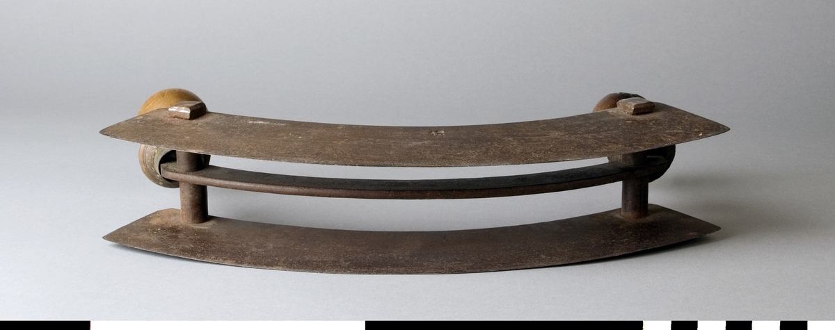 Kniv, dubbelbladig hackkniv, av stål med handtag av trä. De svarvade handtagen sitter på var sin sida av en bygel. De två bladen är fästa i bygeln med bustningar, nitade.
I de två bladen är siffrorna 12 instansade.

Ett av trähandtagen är defekt.