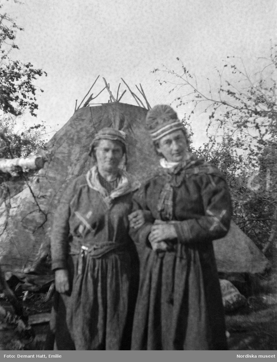 Siri Turi (gift med Johan Turis bros Aslak) och Emilie Demant Hatt utanför Siris kåta i Laimo-Sidaen, Talma sameby, Jukkasjärvi socken, Torne lappmark. Emilie Demant Hatt bodde hos Siri från våren 1907 till 1908.
