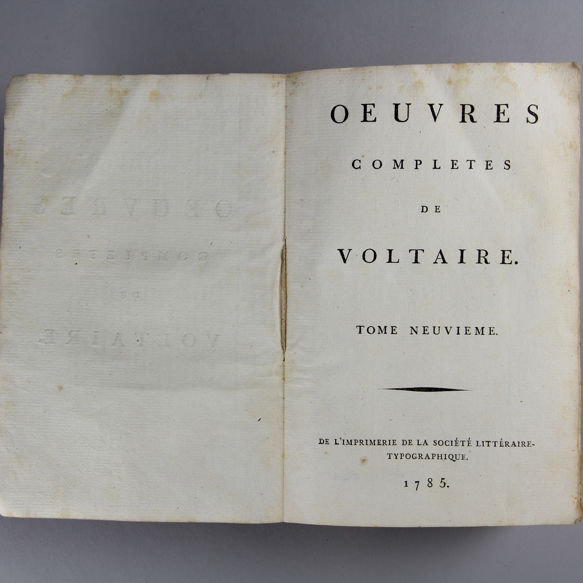 Bok, häftad,"Oeuvres complètes de Voltaire." del 9, tryckt 1785.
Pärm av gråblått papper, skurna snitt. På ryggen pappersetikett med tryckt text med volymens namn och nummer. Ryggen blekt.