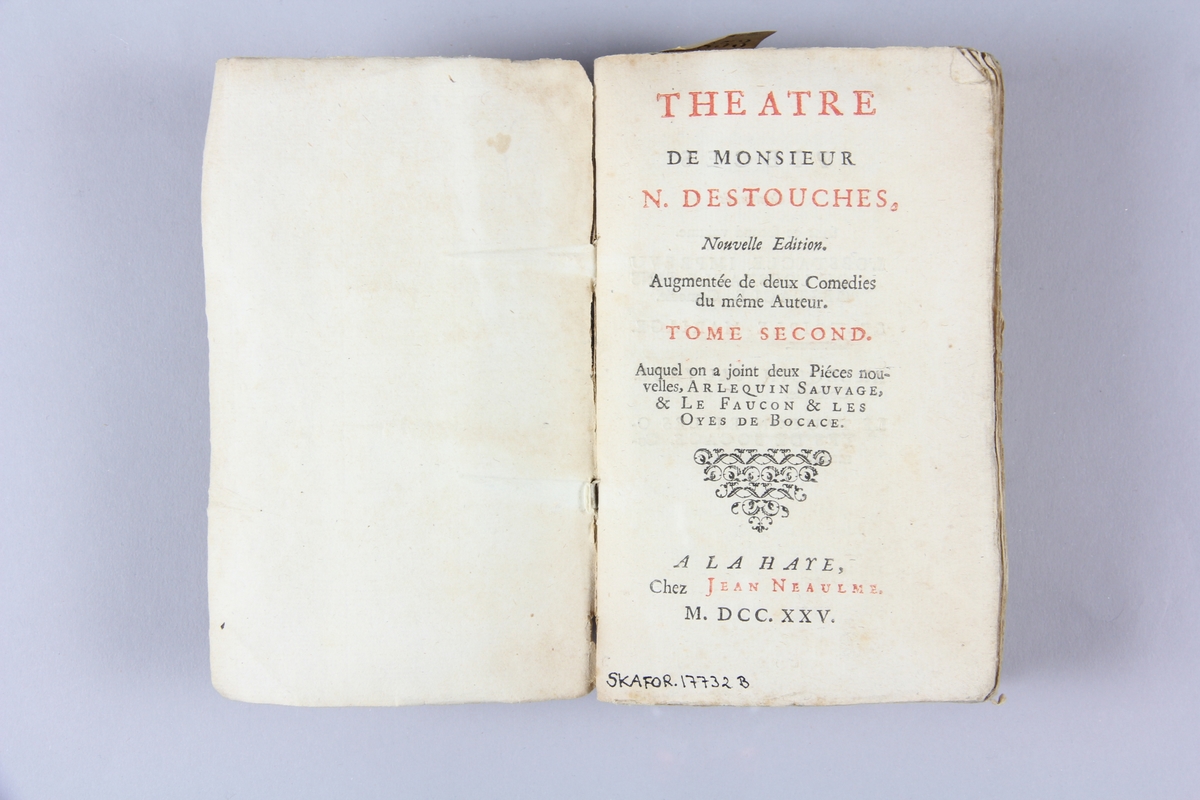 Bok, häftad, "Theatre", del 2, skriven av N. Destouches, tryckt i Haag 1725.
Pärm av marmorerat papper, oskurna snitt. På ryggen klistrade pappersetiketter med volymens namn och samlingsnummer. Ryggen blekt.