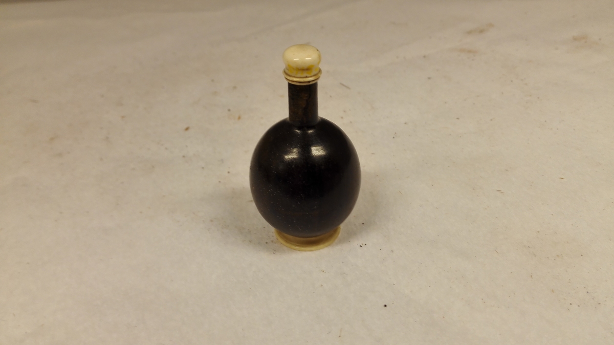 Form: Kuleforma flaske med tunn hals,utvendige gjenger til korken,og innvendige gjenger under til proppen. Frå barndomsheimen til gjevaren.