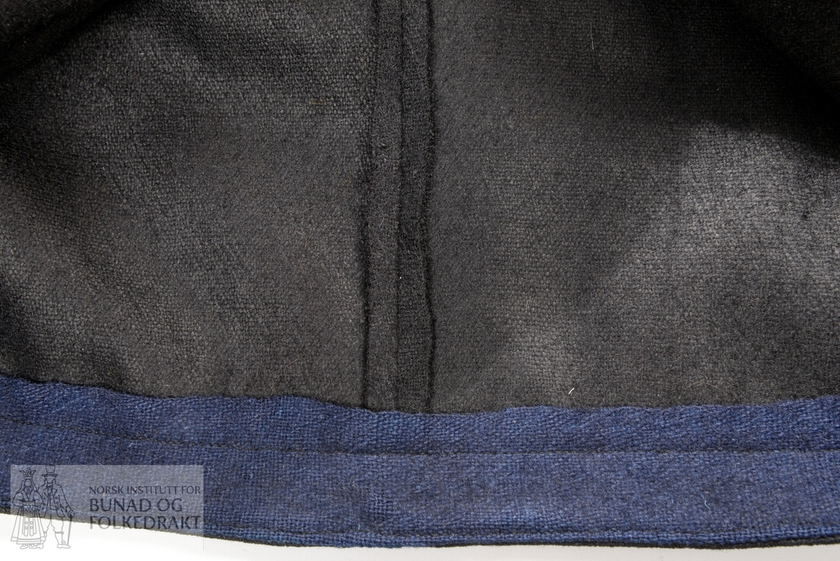 Stakk og trøye, sammensydd. Svart ull, men ikke samme stoff i stakk og trøye. Trøyestoffet er mer finvevd enn i stakken. 
Trøye i svart kypervevd ullstoff, kantet med rødt mønstervevet bånd. Rød bunnfarge med motiv i lilla, blått og svart. Lukkes midt foran med fire hekter. Hel rygg, bakovertrekte sidesømmer. Søm på skulder. Ermene er lagt i to legg ved skulder. Erme med splitt, lagt i legg til linning som lukkes med en hekte. Trøye og stakk er uforet. Et blått, ganske grovt, lerretsvevd ullstoff er brukt som belegg inne i trøya og som skoning på stakken. 

Stakk i lerretsvevd ull, rynket til linningen. Påsydd belte av mønstervevet bånd med rød bunn og motiv i lilla, blått og svart. Beltet har en smal kant av svart fløyelsbånd på hver side midt foran. Linning av svart bomullsstoff med innvevd mønster i hvitt. Stakken er sydd av 6 høyder stoff. Maskinsøm.