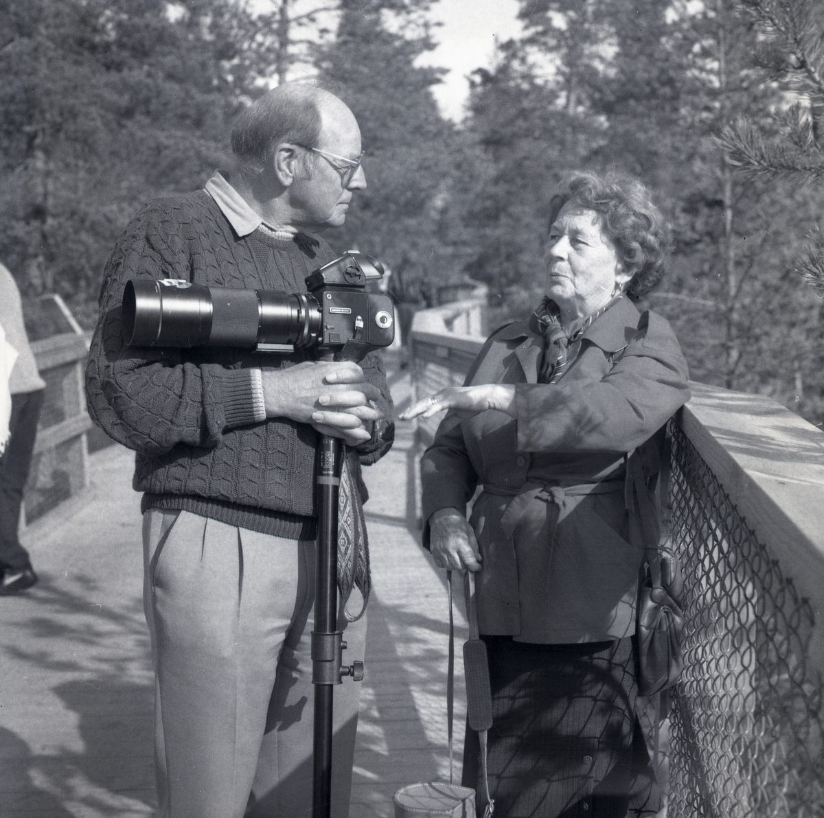 En man och en kvinna står på en gångbrygga vid Järvzoo i Järvsö 1991. Mannen håller i en kamera med stativ.