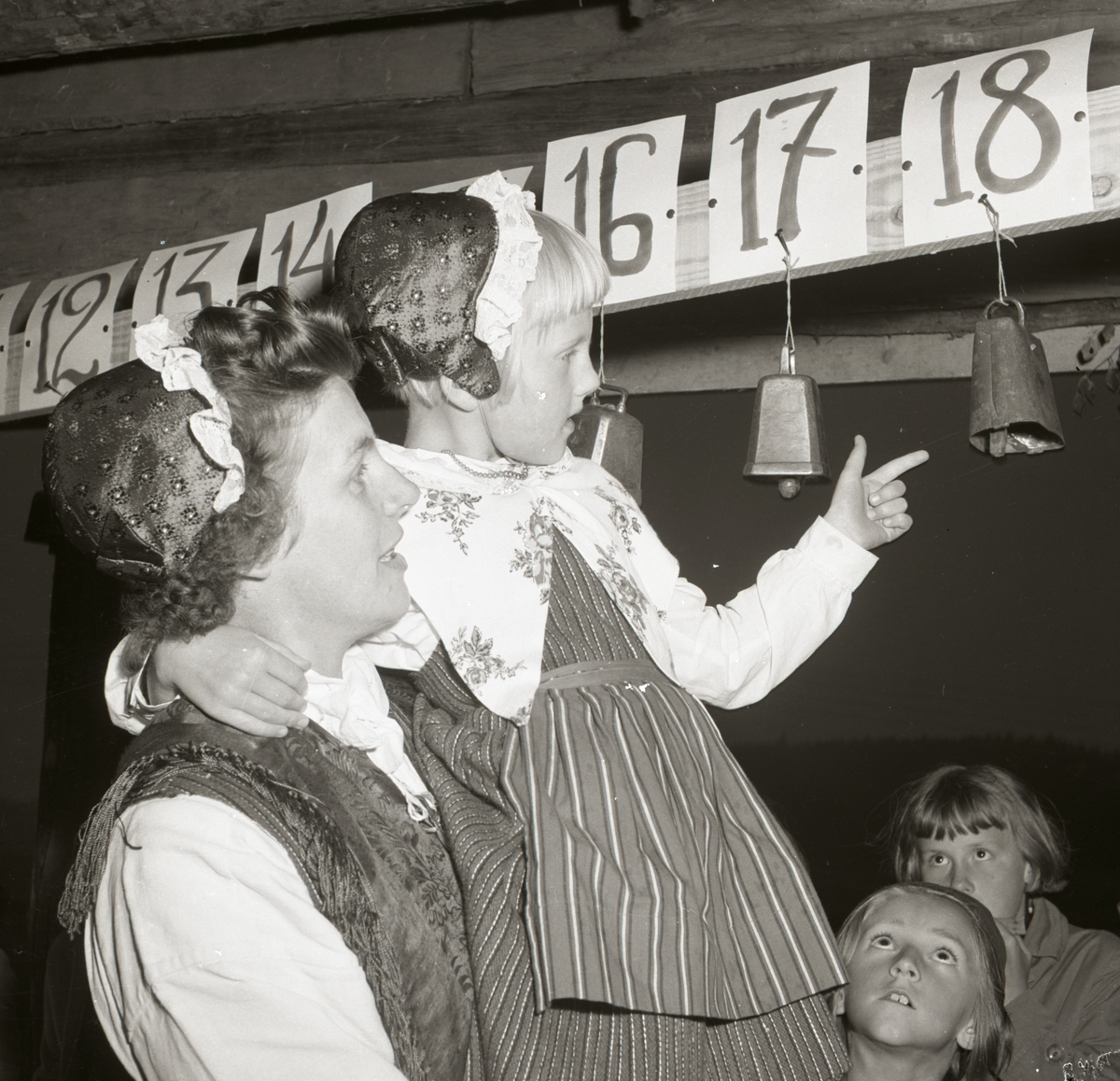 En kvinna och en flicka iklädda hembygdsdräkter, tittar på koskällor under Rengsjö hembygdsfest och skällfest, 24 augusti 1958.