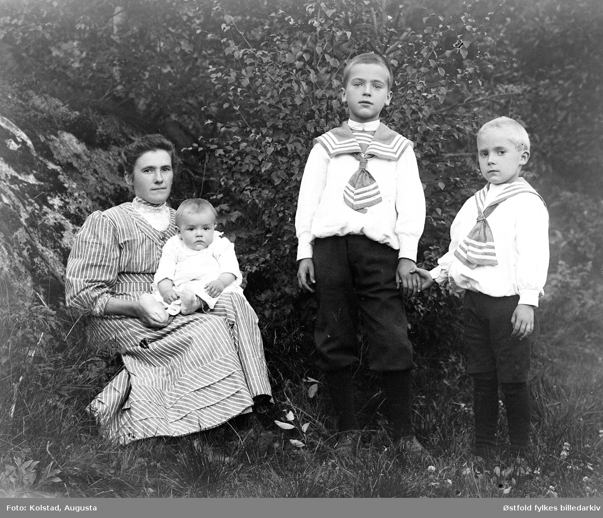 Gruppeportrett av mor med tre barn. Ukjente.