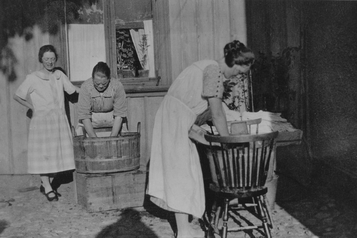 Tre kvinnor tvättar på gården Solgatan 7. Kvinnan i mitten är Amanda Dahlgren som står med tvättbräda i en balja. De två andra kvinnorna är hennes döttrar.