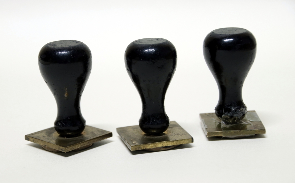 Tre metallstempler med sort trehåndtak. Et av stemplene er teipet grunnet løs del.