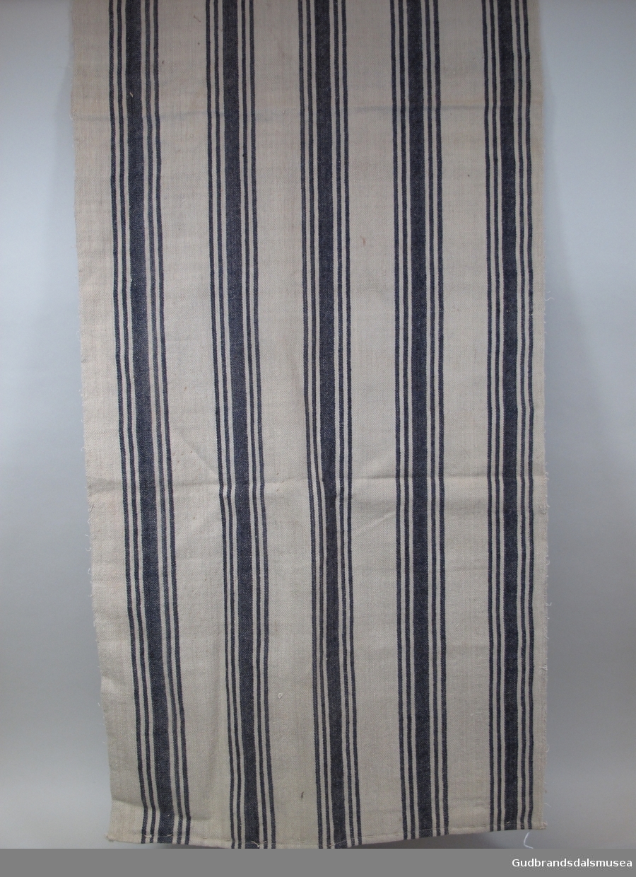 1 lengde vevd klede på ca. 370 cm lagt sammen og sydd i lengden, slik det utgjør halvdelen av et dynetrekk til underdyne, dvs. madrass. 1 av 3 kleder med likt stoff, veving og mønster med brede, vertikale striper i blått.