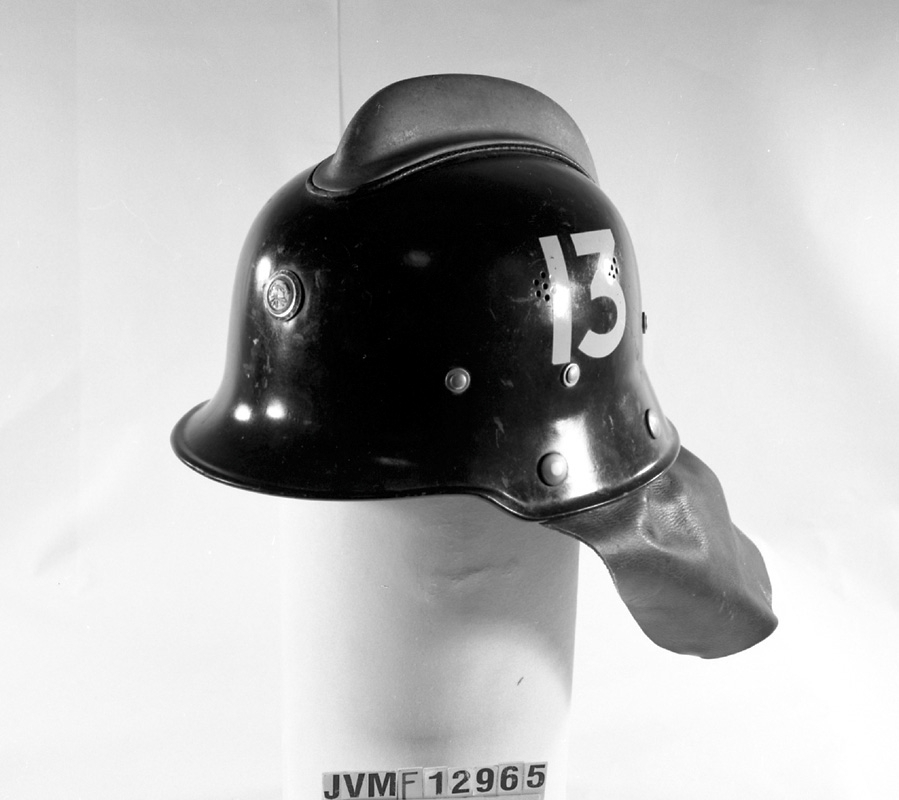 Brandhjälm, svart med nummer 13 i vitt på sidorna. På insidan av hjälmen står det "PATS BBH" i lädret.


Historik: Brandhjälmen har använts inom SJ verksbrandkår och tillhör brandbilen på Jvm.