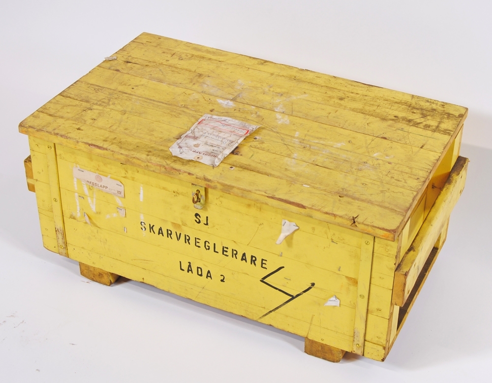 Skarvreglerare i två stycken gulmålade transportlådor av trä. Skarvreglerarens delar är också gula. På den ena lådan (:1) står det "SJ SKARVREGLERARE LÅDA 1" samt "SUO. ML.", vilket är förkortning för signalunderhållsområde Mellerud. Lådan är även märkt "27407". På den andra lådan (:22) står det "SJ SKARVREGLERARE LÅDA 2" samt "4". På låda 2 sitter även en adresslapp med godsavsändare SJ Huvudförråd, Bollnäs och mottagare "SJ Banområde Stationshuset Storvik".
Skarvregleraren består av en hydraulpump (handpump) (:24), ett handtag till pumpen (:25), sex stycken spännklotsar (:26-31), två stycken spännanordningar (:2-3), tio stycken shims (:6-15), sex stycken isolerskarvar (:4-5, :16-19), ett snörnystan (:20), fjorton stycken plastringar (:21) samt en tillhörande tratt för påfyllning av hydraulolja (:23). I lådan fanns även en följesedel och en instruktion från november 1965 "SJ CENTRALFÖRVATNING BANAVDELNINGEN Rationaliseringskontoret". Instruktionen, som består av ett A4 ark med text och bild på båda sidor, är helt dränkt i hydraulolja. 

Text på instruktionen "Skarvregleraren är avsedd för användning vid signalunderhållsområdenas arbeten med isolerskarvar. 
Den består av 8 spännklotsar, (4 st för SJ50 och 4 st för SJ34, SJ41 och SJ43) 2 st hydrauliskt arbetande spännanordningar, hydraulpump samt 8 st mellanlägg. 
Hydraulpump: Dowty HP 5, arbetstryck 150 kg/cm2
Hydraulolja: H O L 25 (fdnr 10 24 732)

Anvisning för uppmontering
Skruva loss skarvjärnen och montera spännklotsarna
Placera spännanordningarna på plats och koppla ihop hydraulslangarna
Koppla hydraulslangen till hydraulpumpen.
Stäng avlastningsventilen.

Anvisning för nedmontering
1.Öppna avlastningsventilen
2.2. Återför hydraulcylindrarnas kolvstänger till utgångsläget
3.Koppla isär hydraulslangarna
4.Lyft loss spännanordningarna
5.Skruva loss spännklotsarna

VIKTIGT! Skydda slagändarna mot grus och andra föroreningar."

Måtten i blanketten gäller låda 1. Låda 2, lxbxh: 760x430x345 mm.

Se bilaga till samlingar.

Modell/Fabrikat/typ: SKARVREGLERARE TYP SRI