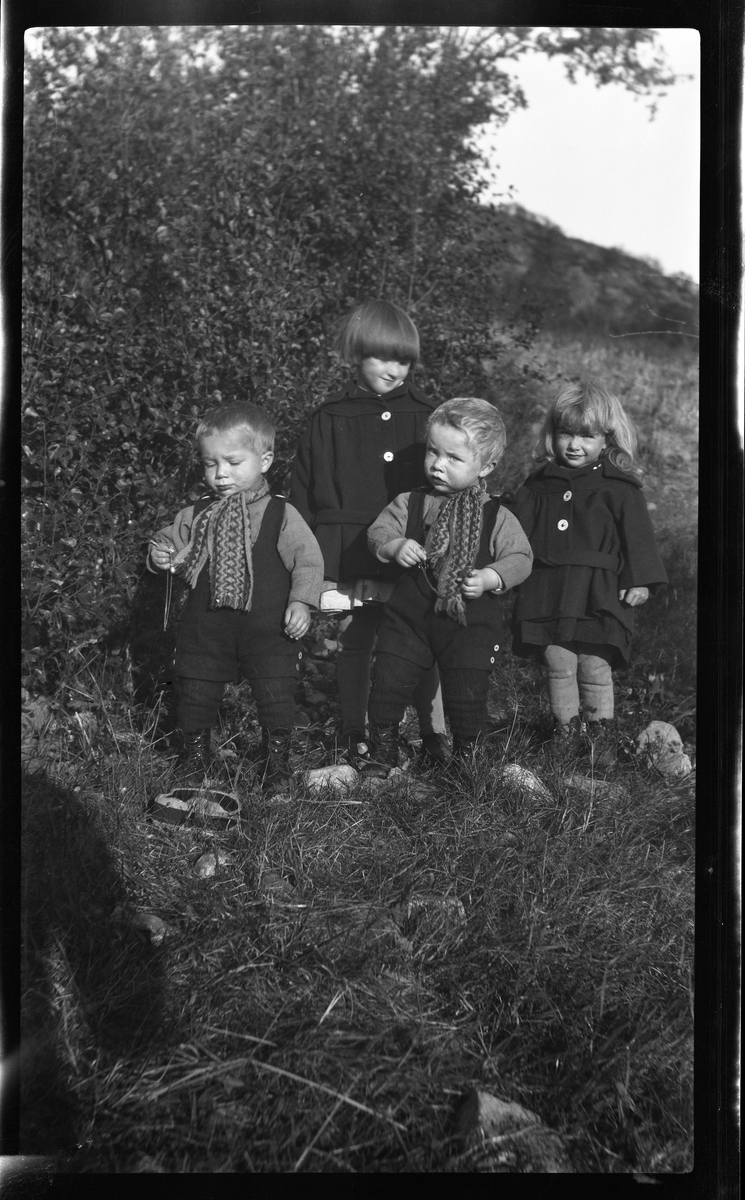 Gruppeportrett av fire barn utendørs.