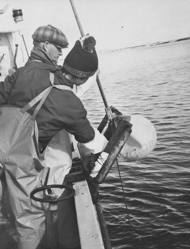 Med båten "Knut" på heimefiske i Dønna. Mann og ungdom i arbeid på dekk.