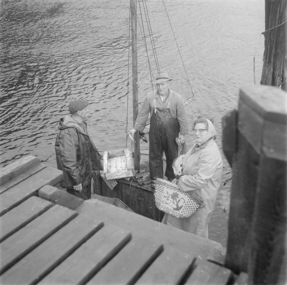 Kvinne som kjøper fisk av to fiskere med sjark.
Ved Jürgensenkaia i Sjøgata.